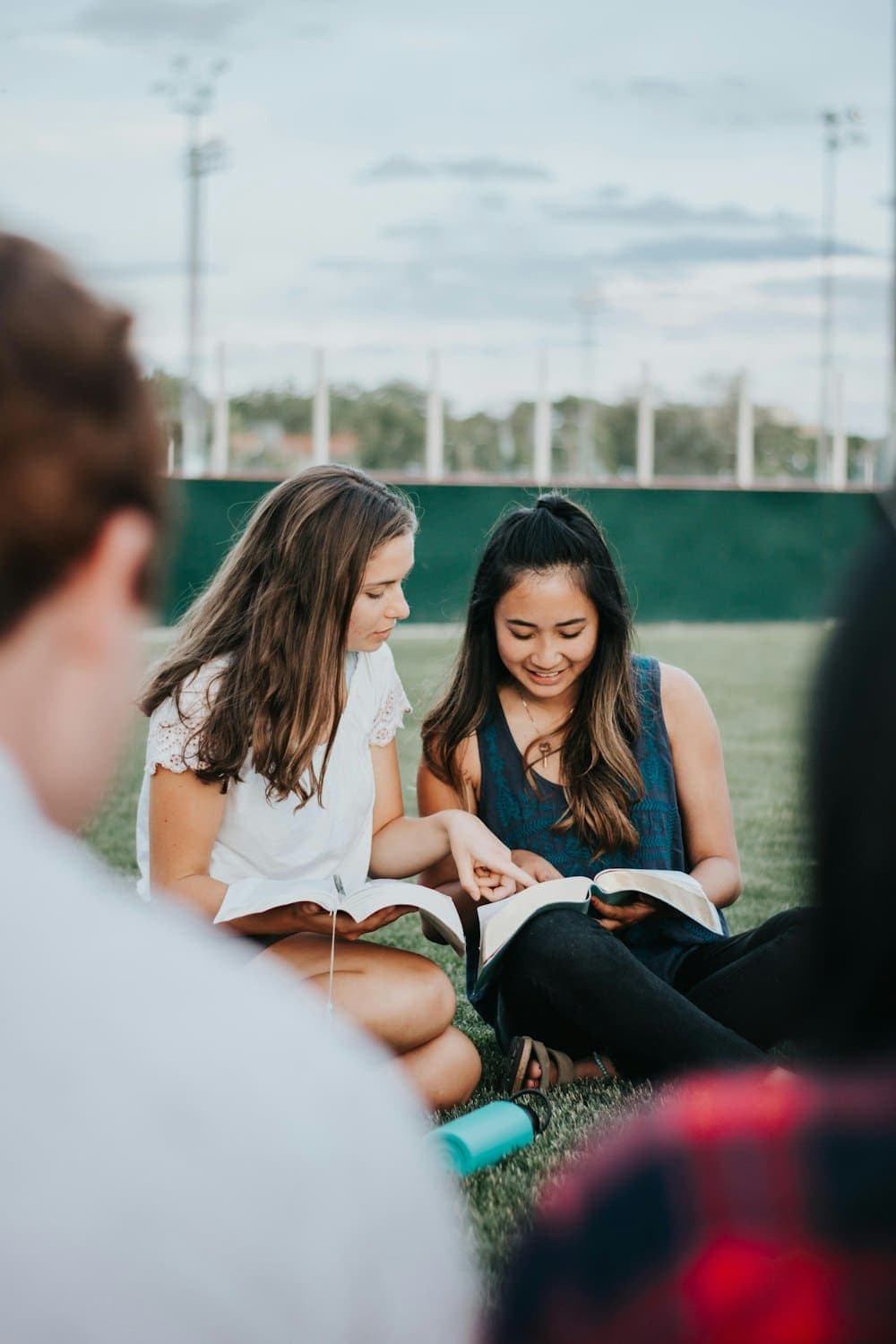 Two friends reading the Bible together outdoors