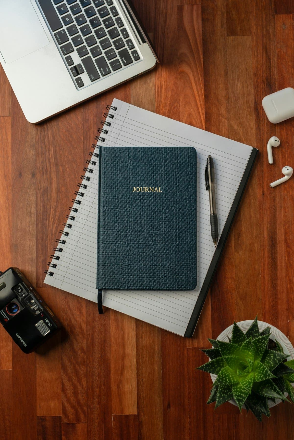 A closed journal and a pen on a wooden desk